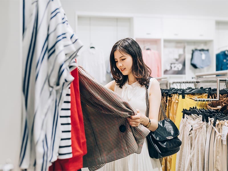 Young Asian woman choosing new clothes in the clothing store