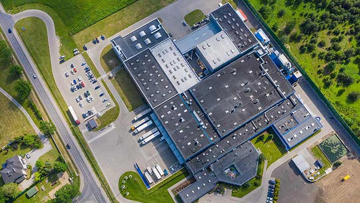 Aerial view of goods warehouse. Logistics center in industrial city zone from above. Aerial view of trucks loading at logistic center