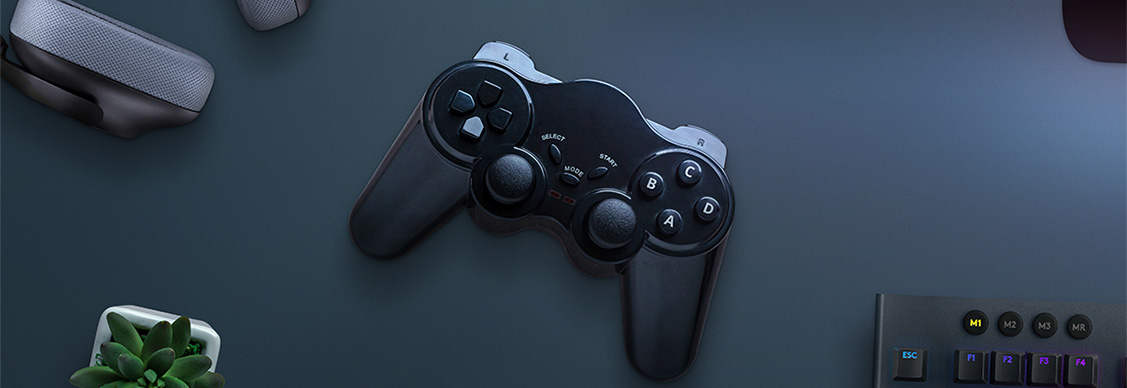 Joypad on desk surrounded with headphones, cooler, keyboard and computer display