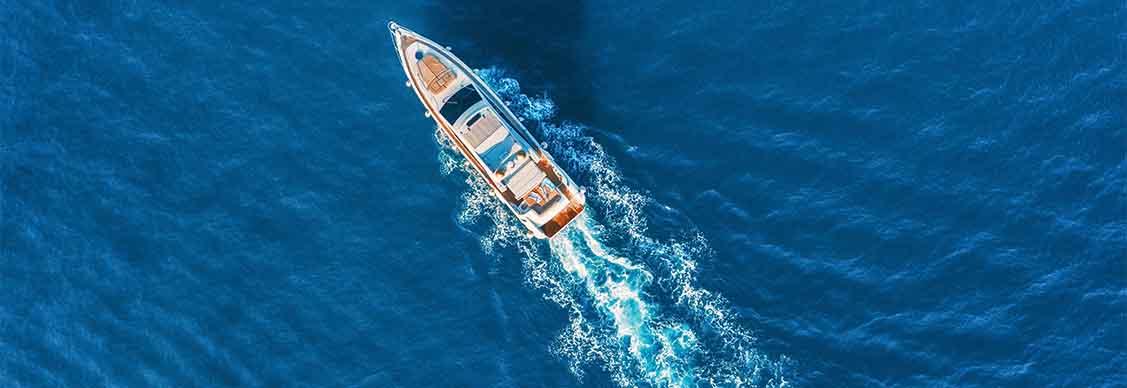 Yacht at the sea in Europe. Aerial view of luxury floating ship at sunset. Colorful landscape with boat in marina bay, blue sea. Top view from drone of yacht. Luxury cruise. Seascape with motorboat