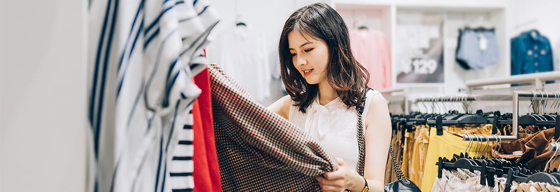 Young Asian woman choosing new clothes in the clothing store