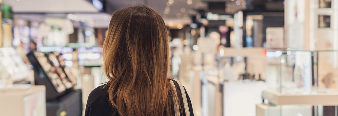 Young Asian woman walking in cosmetics department at the mall.