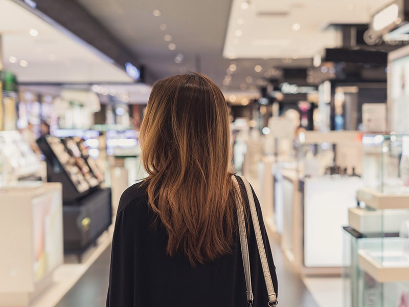 Young Asian woman walking in cosmetics department at the mall.
