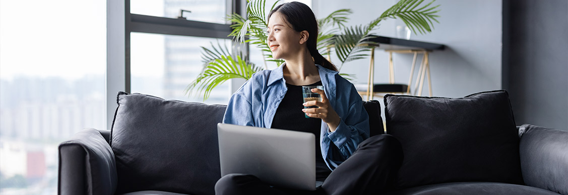 Girl working on laptop while sitting on sofa