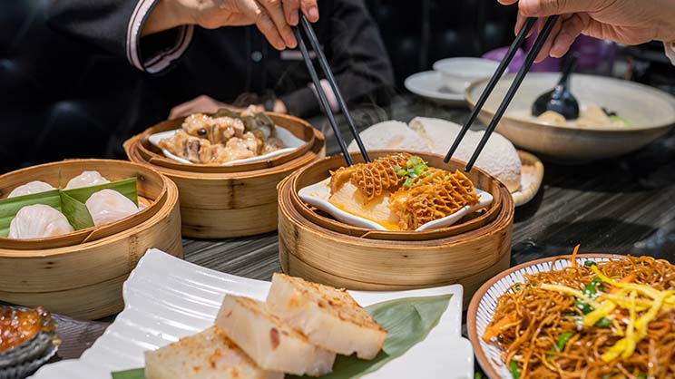 There are bowls of food on the table, and two people are also enjoying their meal.