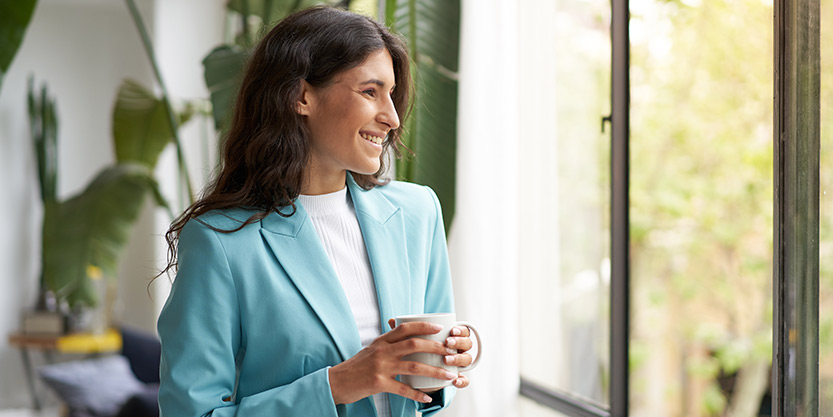 A woman smiling and holding coffee mug