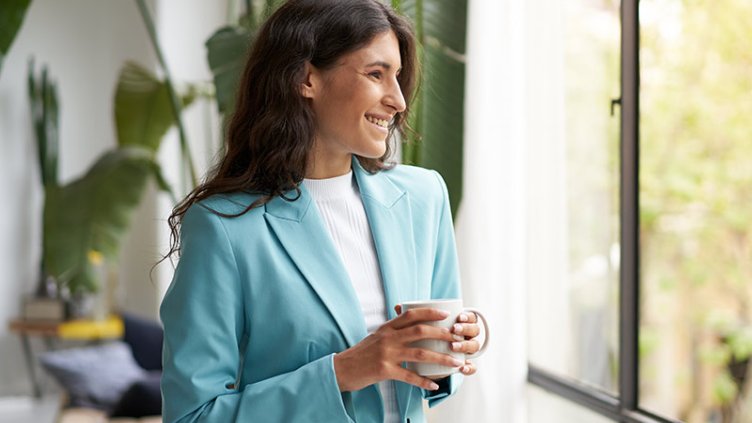A woman smiling and holding coffee mug