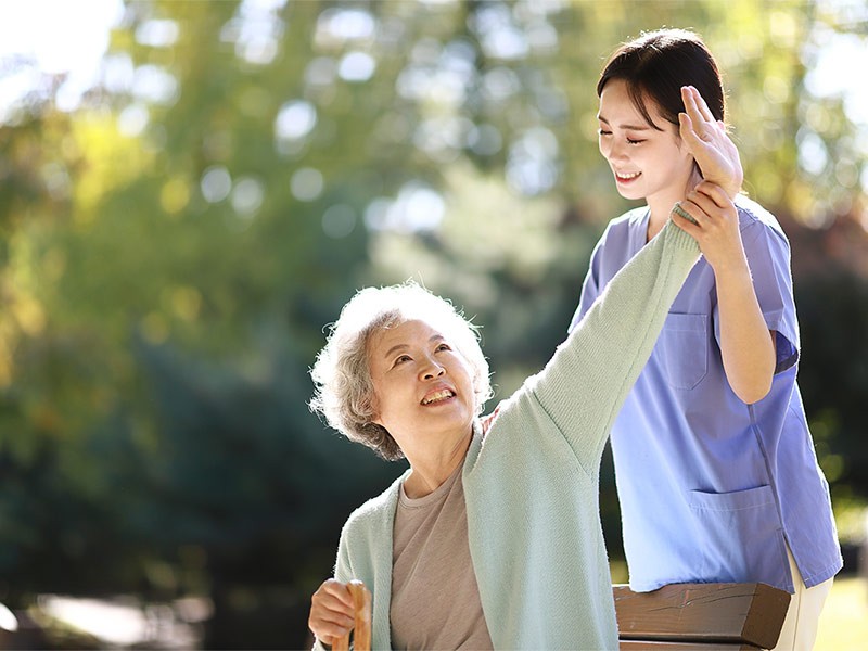 Senior woman stretching with nurse