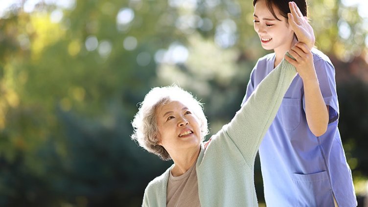 Senior woman stretching with nurse