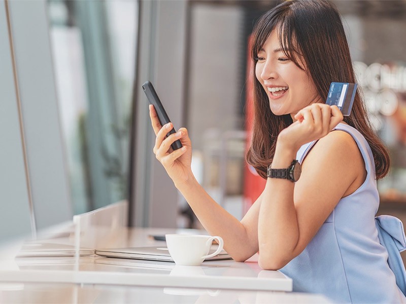 A girl holding a phone and card