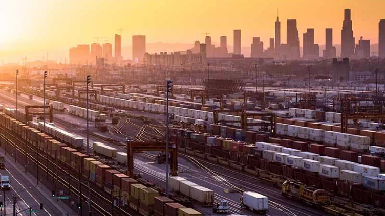 City view with cargo containers on a railway track, being loaded and unloaded