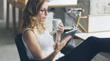 Women reading on tablet and drinking coffee