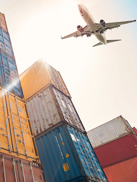A plane flying over a stack of shipping containers