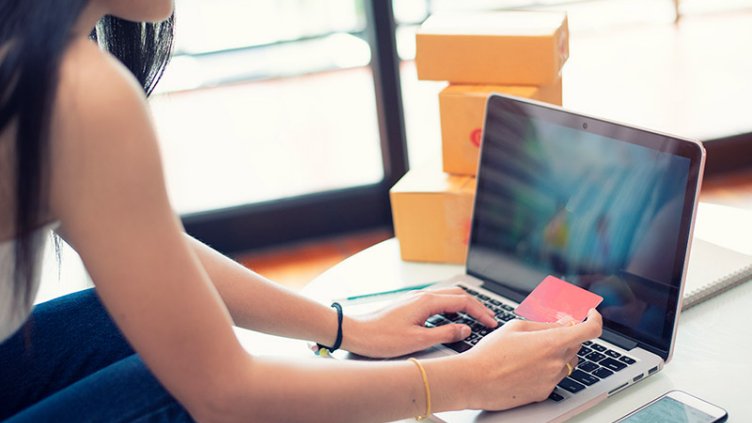 Young woman paying shopping online with a credit card at home