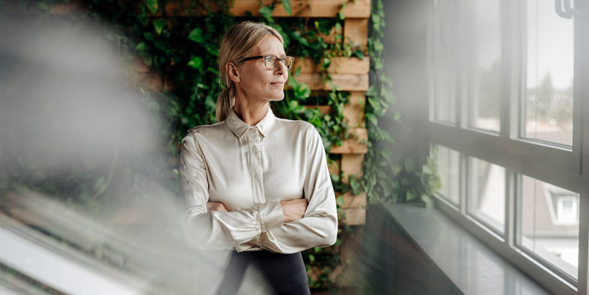 A woman looking the growth of green building through window