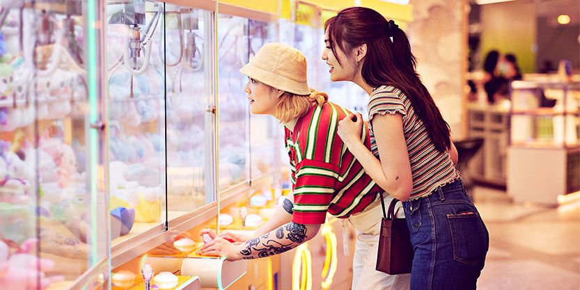 Women playing grabbing game in arcade