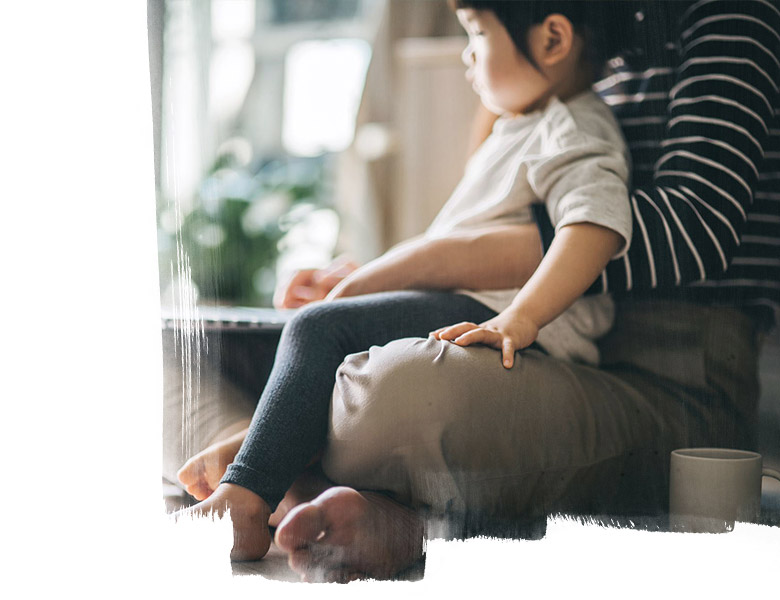 A kid sitting in his father's lap and looking outside as it's Q12020 lockdown