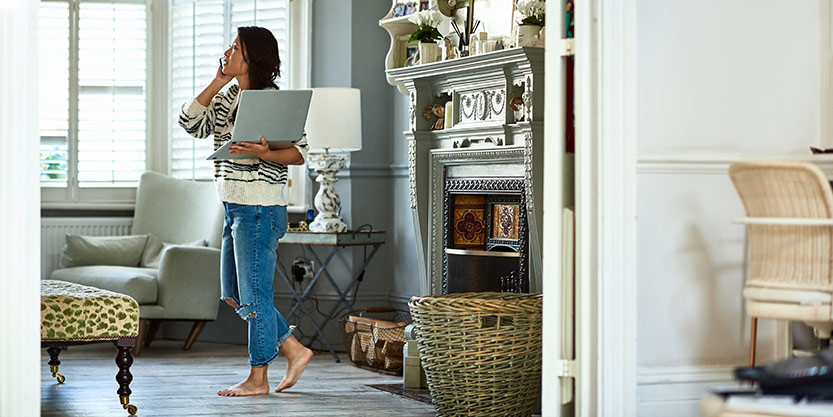 Women standing with a laptop and speaking in mobile