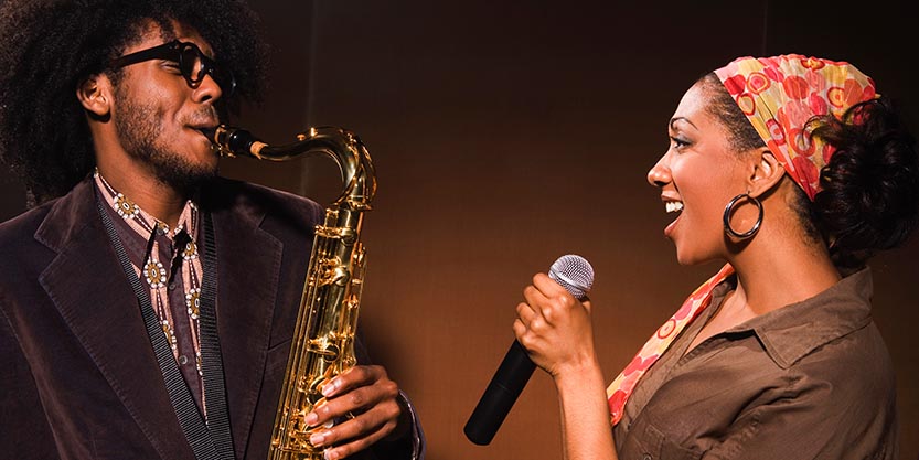 One person plays the saxophone and the other sings