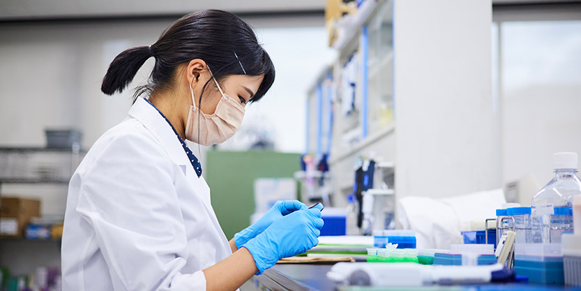 A woman with a mask working in a lab