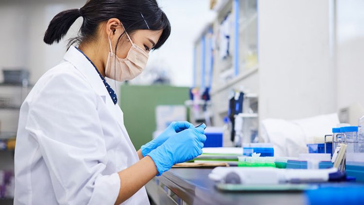 A woman with a mask working in a lab
