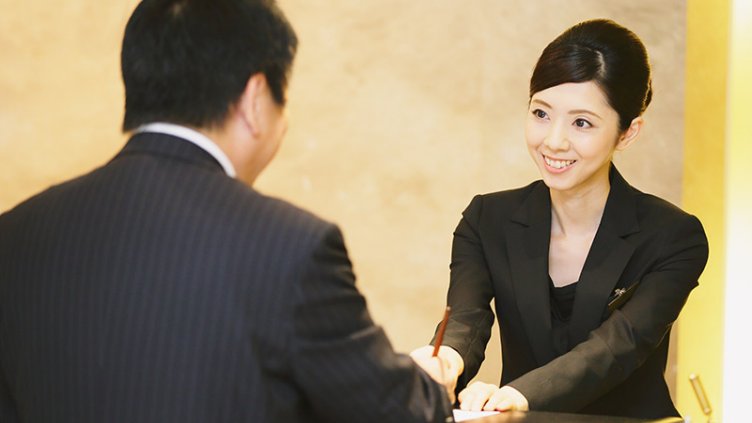 Smiling front-desk lady serving a hotel guest