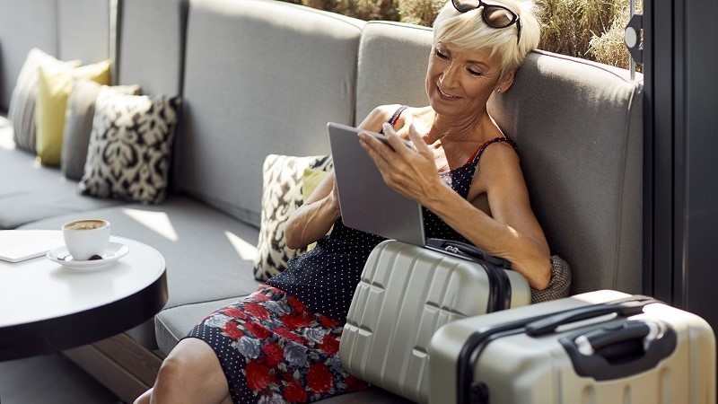 A woman using her tablet while waiting in the hotel with her luggage