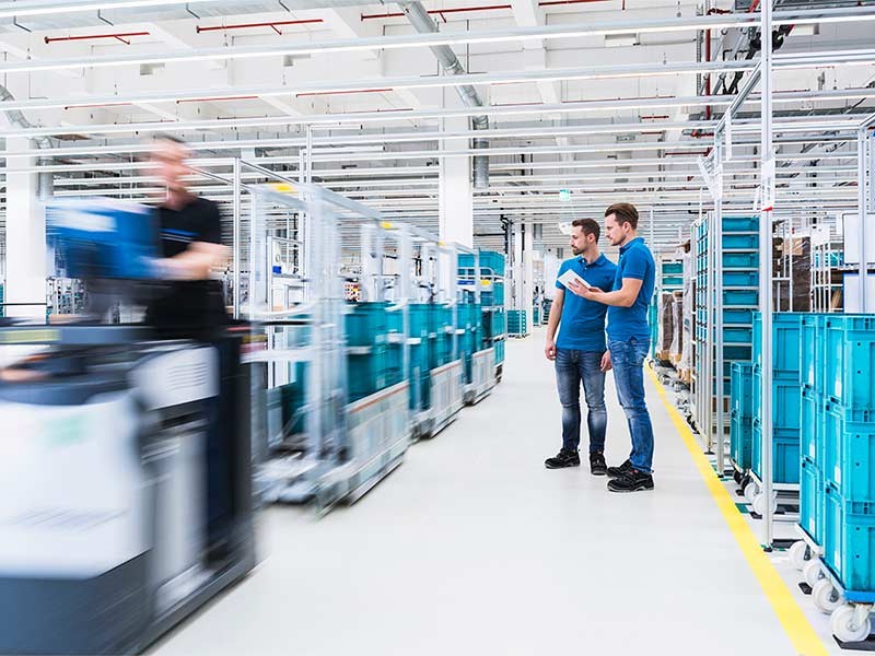 Two men with tablet talking in industrial hall