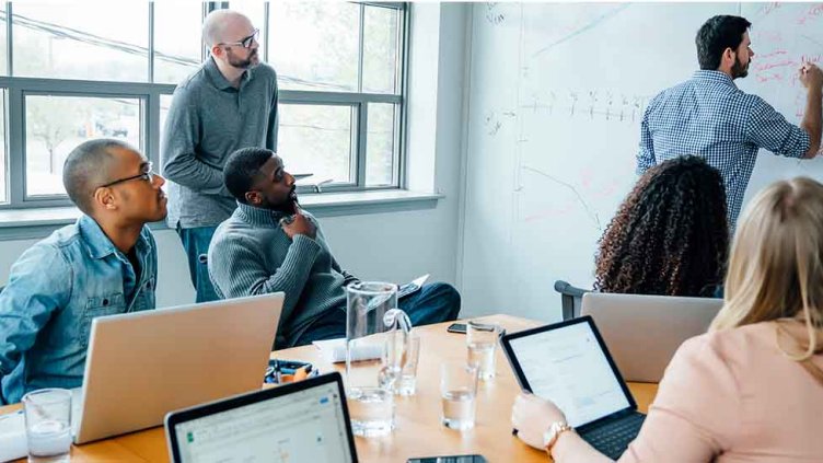 Employees having meeting and discussing the things by writing on the whiteboard inside a meeting room