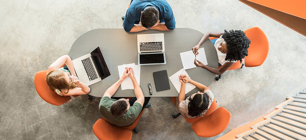 View from above towards five business people around meeting table