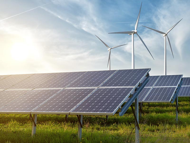 solar panels and wind generators under blue sky on sunset